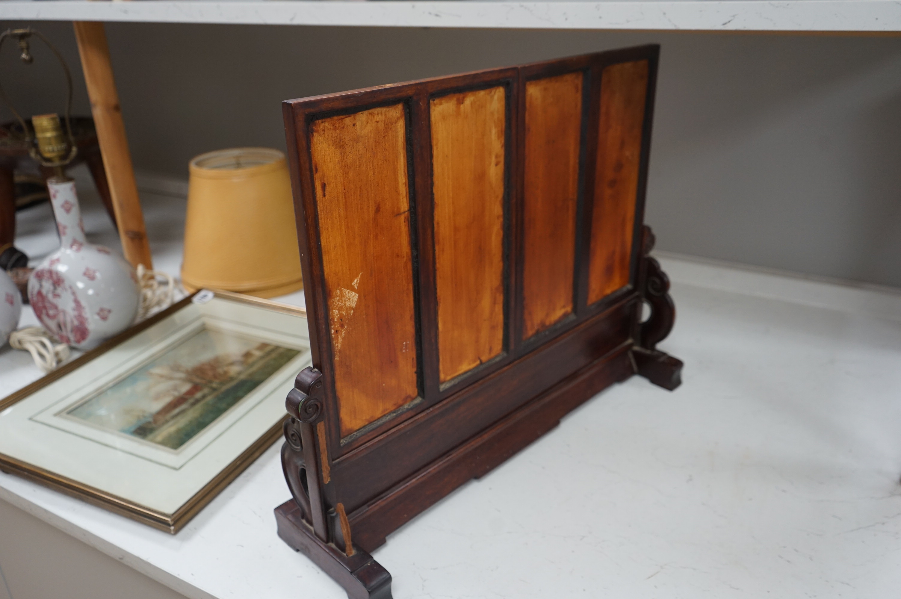 A Chinese four painted porcelain panel and carved hardwood table screen, 54cm wide x 42.5high. Condition - fine staining to one panel and top carved panel of screen missing